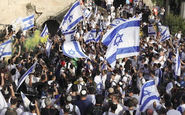 東エルサレムの旧市街につながるダマスカス門前で、国旗を掲げ踊るユダヤ人ら＝共同