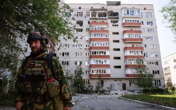 　29日、ウクライナ東部ルガンスク州セベロドネツクの損傷した建物と兵士（タス＝共同）