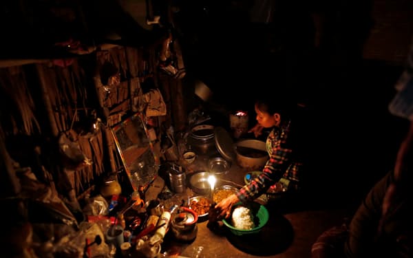 ろうそくの明かりで夕食の支度をするミャンマーの女性（2017年、ヤンゴン郊外）＝ロイター