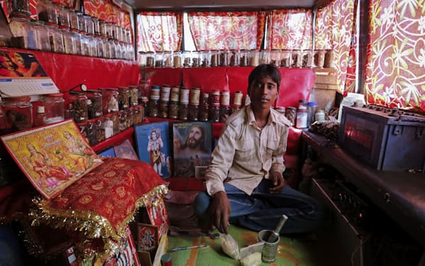伝統療法アーユルベーダの薬品ショップで店番をする青年（2014年、インド西部ムンバイ）＝ロイター
