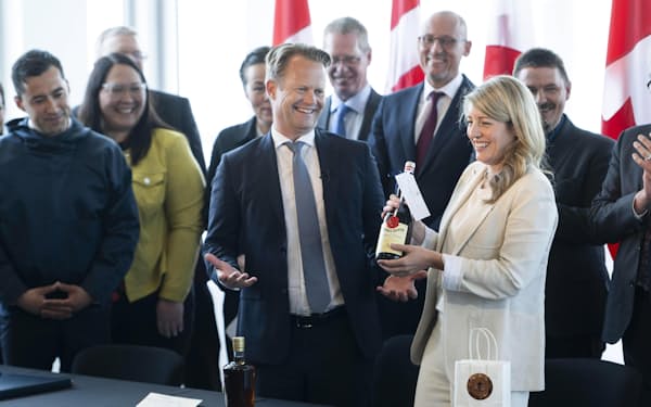 ハンス島の分割領有で合意し、酒のボトルを交換するカナダのジョリー外相（手前右）とデンマークのコフォズ外相（中央）＝14日、オタワ（カナダ通信、AP＝共同）