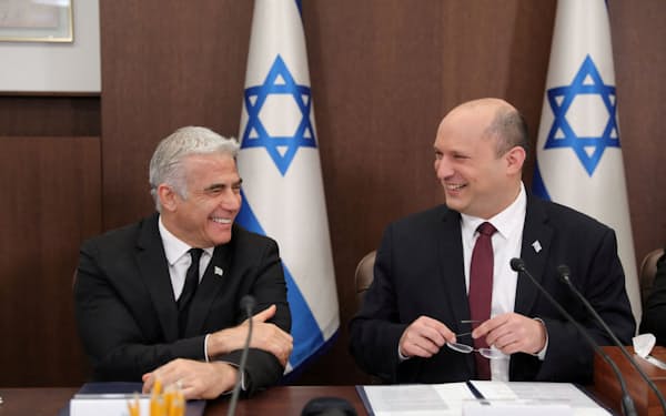 イスラエルのベネット首相㊨とラピド外相は１年前の政権発足時、首相ポストの輪番制で合意していた（19日、エルサレム）＝ロイター