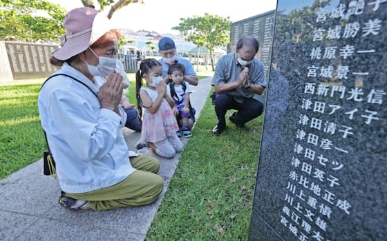 沖縄戦犠牲者の名前が刻まれた「平和の礎（いしじ）」の前で手を合わせる遺族（23日午前、沖縄県糸満市の平和祈念公園）