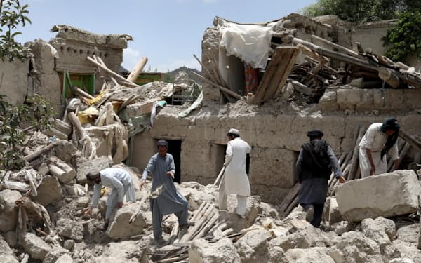 23日、アフガニスタン東部パクティカ州で、がれきの中を捜索する人々＝ロイター