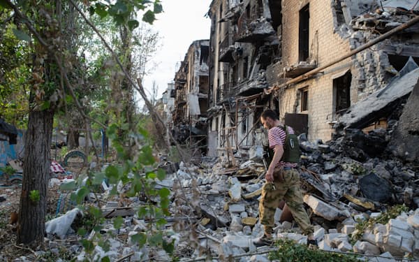 23日、セベロドネツクで破壊された建物脇を歩く地元の男性＝タス共同