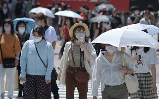 強い日差しの中、日傘を差して歩く人たち（25日午前、東京都渋谷区）