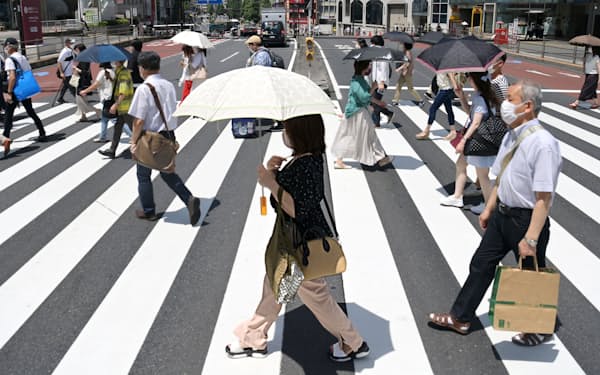 強い日差しの中、日傘を差して歩く人たち（29日午前、JR新宿駅前）