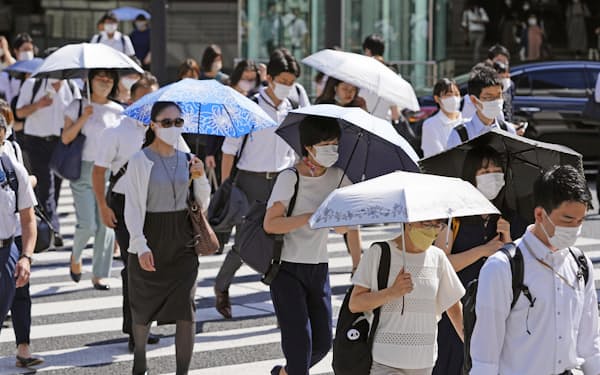 強い日差しの中、日傘を差して歩く人たち（6月29日午前、JR東京駅前）=共同