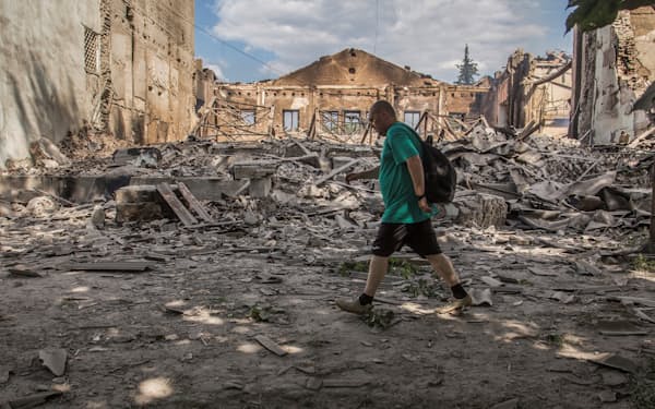 リシチャンスクでロシア軍の攻撃が続く中、破壊された建物の前を歩く市民（17日）＝ロイター
