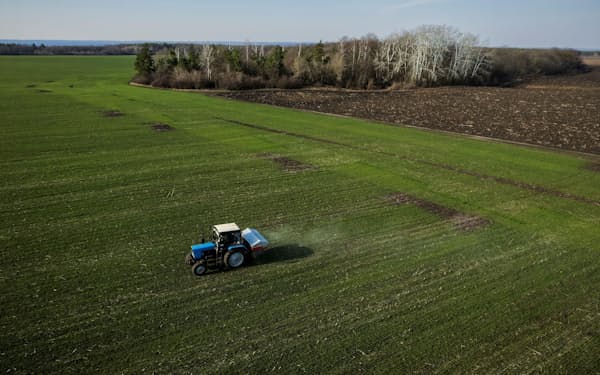 　空爆を受けた村の近くの小麦畑で肥料をまくトラクター＝4月、ウクライナ東部ハリコフ郊外（ロイター）
