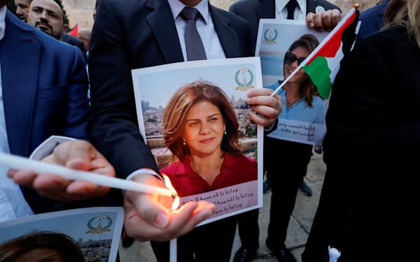 取材中に亡くなった記者の写真を掲げて追悼する人々（5月、ヨルダン川西岸地区）＝ロイター