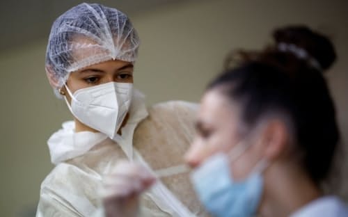 2022年6月、フランス西部ナントに近いレ・ソリニエールの新型コロナウイルス検査センターで、利用者の鼻腔ぬぐい液を採取する医療従事者。（PHOTOGRAPH BY STEPHANE MAHE, REUTERS）
