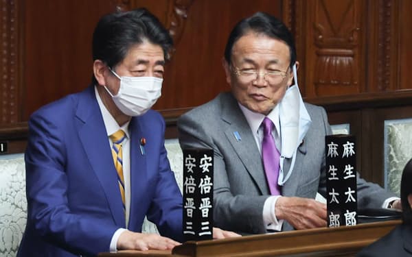 衆院本会議場で言葉を交わす自民党の麻生副総裁（右）と安倍元首相（2022年3月）
