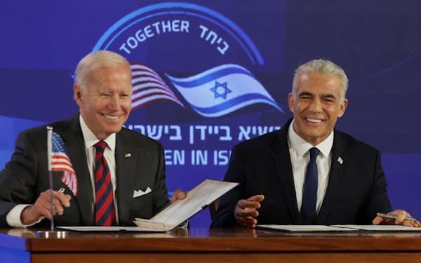 14日、エルサレムで共同宣言に署名するイスラエルのラピド首相（右）とバイデン米大統領=ロイター
