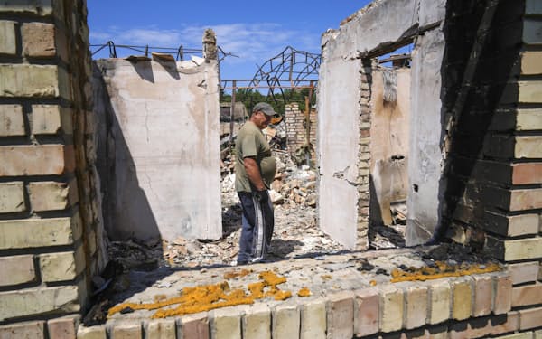 　ウクライナの首都キーウ近郊ブチャで、破壊された自宅を片付けに来た男性＝6月（共同）