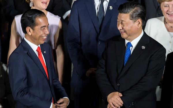2019年に大阪で開いたＧ２０首脳会議で中国の習近平国家主席㊨と話すインドネシアのジョコ大統領＝ロイター