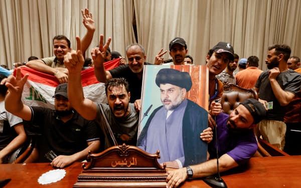 一時占拠した国会議事堂でサドル師の肖像を掲げる支持者ら（27日、バグダッド）＝ロイター