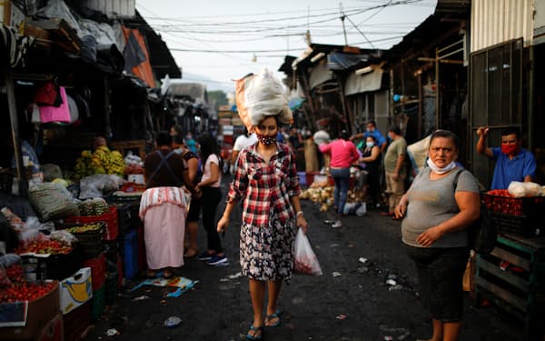 エルサルバドルの市場でマスクを付けて買い物を運ぶ女性＝ロイター