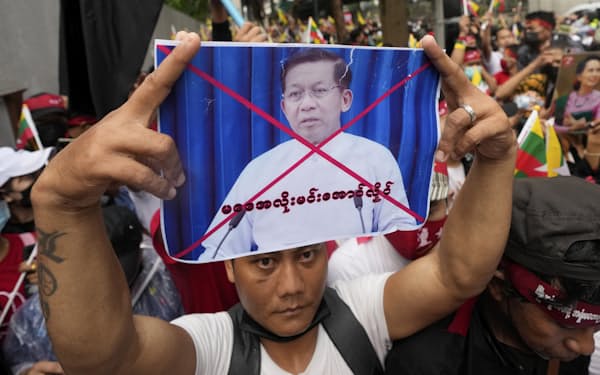 A Myanmar nationals living in Thailand holds a picture of Senior Gen. Min Aung Hlaing, head of the military council as they protest outside Myanmar's embassy in Bangkok, Thailand, Tuesday, July 26, 2022. International outrage over Myanmar's execution of four political prisoners intensified Tuesday with grassroots protests and strong condemnation from world governments, as well as fears the hangings could derail nascent attempts to bring an end to the violence and unrest that has beset the Southeast Asian nation since the military seized power last year.(AP Photo/Sakchai Lalit)