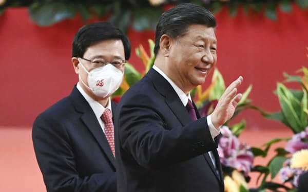 　香港返還25年記念式典で、手を振る中国の習近平国家主席（右）。左は香港特別行政区の李家超新長官＝1日、香港（AP＝共同）