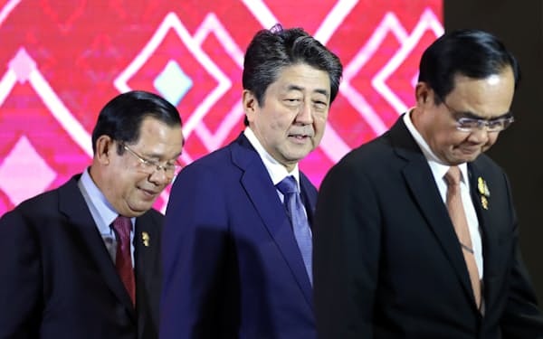 日本ASEAN首脳会議で安倍氏と並ぶカンボジアのフン・セン㊧、タイのプラユット両首相（バンコク、2019年11月）＝ロイター