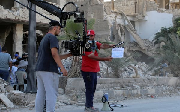 破壊された建物の前で撮影する映画「ホーム・オペレーション」のスタッフ（7月17日、ハジャルアスワド）=ロイター