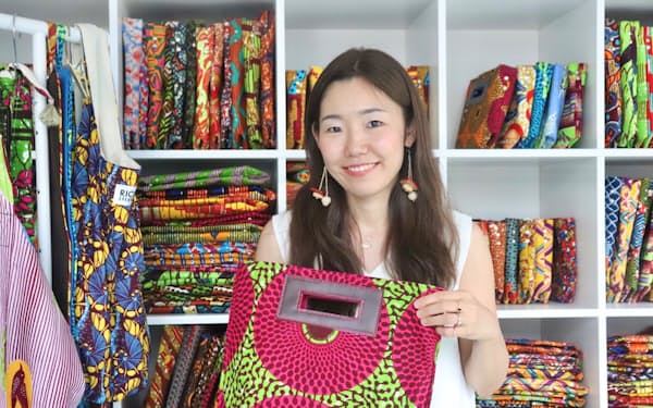 アフリカ布を使った商品に囲まれて笑顔を見せる「RICCI EVERYDAY」代表の仲本千津さん（東京都新宿区の直営店で）