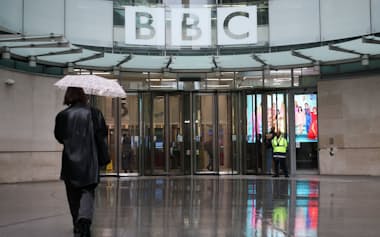 A person walks with an umbrella outside BBC Broadcasting House, after Director General Tim Davie and CEO of BBC News Deborah Turness resigned on Sunday, November 9, following accusations of bias at the British broadcaster, including in the way it edited a speech by U.S. President Donald Trump, in London, Britain, November 14, 2025. REUTERS/Isabel Infantes