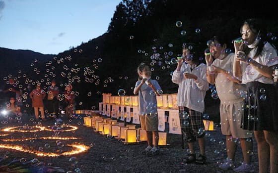 犠牲者の冥福を祈り、灯籠の横でシャボン玉を吹く子どもたち（11日、群馬県上野村）
