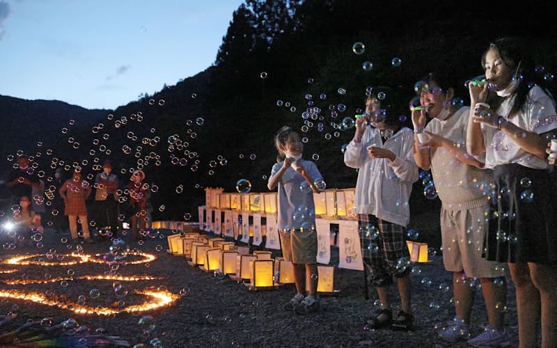 犠牲者の冥福を祈り、灯籠の横でシャボン玉を吹く子どもたち（11日、群馬県上野村）