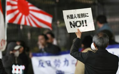 ヘイトスピーチを行う団体(奥)に抗議する男性(2017年、東京・新宿)