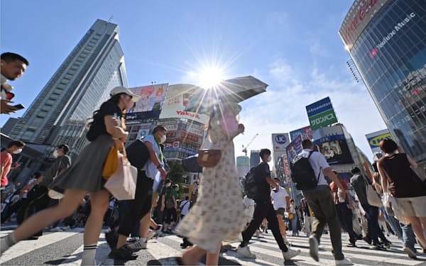 厳しい暑さの中、日傘を差して歩く人たち（31日、東京都渋谷区）