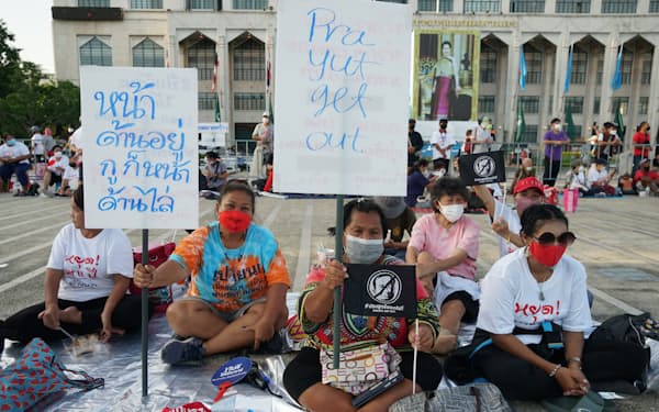 「プラユットは出ていけ」と書かれたプラカードを掲げるデモ参加者（23日、バンコク）
