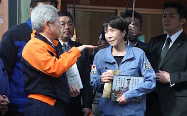 応急仮設住宅を訪れ、珠洲市の泉谷満寿裕市長(左)から説明を受ける高市首相(7日、石川県珠洲市)=代表撮影