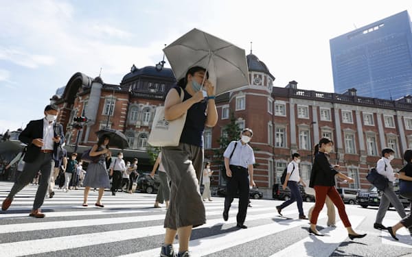 　強い日差しの中、日傘を差して歩く人たち＝1日午前、JR東京駅前