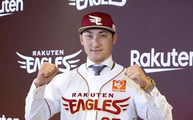 楽天の入団記者会見でユニホームを着てポーズをとる、DeNAから移籍した伊藤光(10日、楽天モバイルパーク宮城)=共同