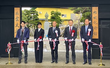 威風を取り戻した結城豊太郎記念館表門の前でテープカットに臨む山形県南陽市の白岩市長㊥ら。奥に結城の銅像が見える(13日、南陽市)