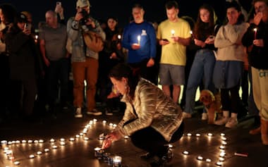 A woman lights a candle during a vigil near the beach, held after a fatal shooting at Sydney's Bondi Beach during Hanukkah celebrations, in Tel Aviv, Israel, December 14, 2025. REUTERS/Ronen Zvulun