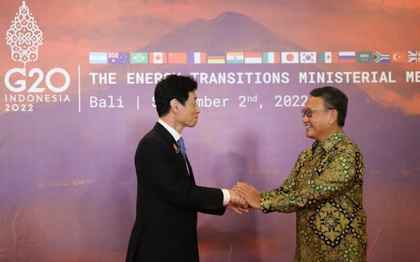 議長国インドネシアのアリフィン・エネルギー・鉱物資源相とあいさつする西村経産相㊧（インドネシア・バリ島＝AP）