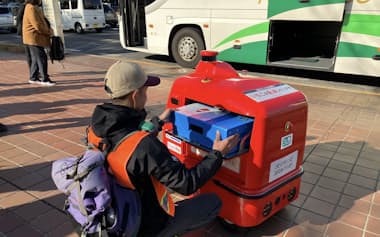 高速路線バスから自動配送ロボットへ荷物を積み替える(16日、名古屋市)