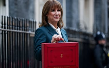 ダウニング街11番地の公邸前で年次予算案の演説用資料の入った赤い箱「レッドボックス」を報道陣に見せるリーブス英財務相(11月26日、ロンドン)=ロイター