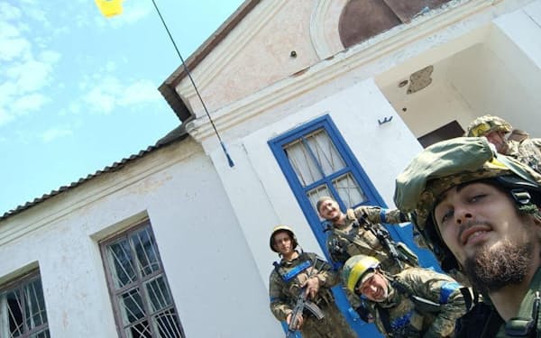 10日、奪還した東部ハリコフ州の村で国旗を掲げるウクライナ部隊＝ウクライナ軍提供・ロイター