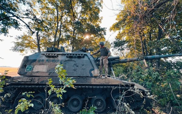 ウクライナのハリコフ地方で、侵攻するロシア軍に反撃して捕獲したロシアの2S19 Msta-S自走榴弾砲の上に立つウクライナ軍兵士＝ウクライナ軍提供・ロイター