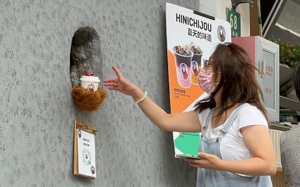 壁に開いた穴からぬいぐるみの熊の手がコーヒーを渡すサービスが人気となった（中国・上海市）