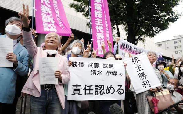 株主代表訴訟の判決後、東京地裁前で「株主勝利」などと書かれた紙を掲げ喜ぶ原告側弁護士や関係者（7月13日）