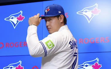 米大リーグ、ブルージェイズの入団記者会見で背番号「7」のユニホームに袖を通した岡本和真内野手=6日、トロント(共同)