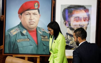 チャベス前大統領(写真左)の肖像が掲げられた議会での演説を終えたベネズエラのロドリゲス暫定大統領(写真中央)=ロイター