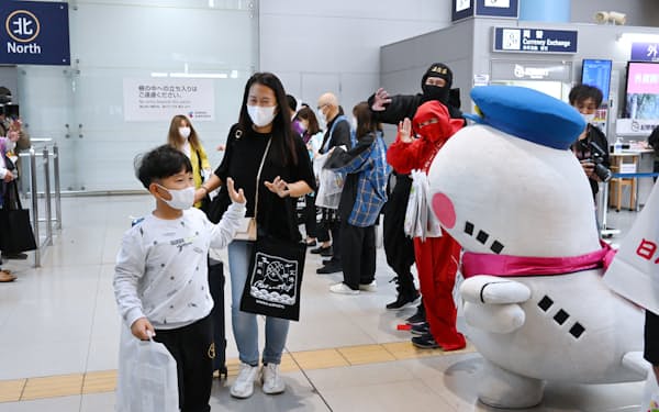 水際対策の緩和初日、訪日客は関西各府県の自治体職員らに出迎えられた（11日午前、関西国際空港）