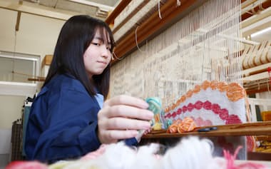 複数の色を組み合わせた横糸を手に取る矢島琉香さん
