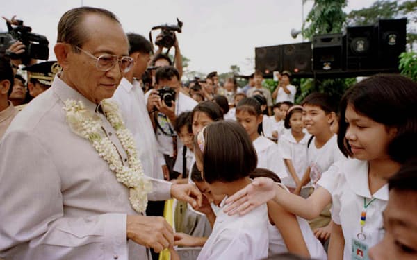 「ピープルパワー革命」の前後に生まれた子どもと触れ合うラモス大統領（1997年２月、マニラ）＝ロイター